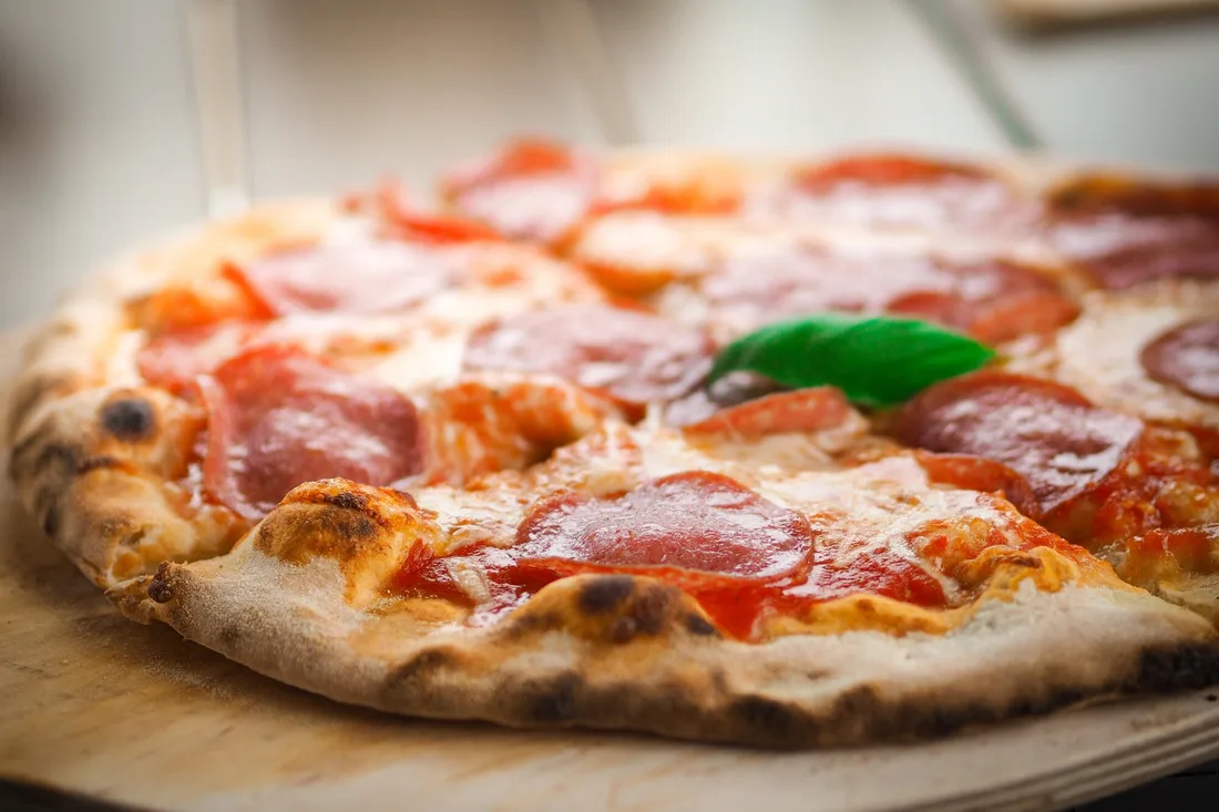 Wood-fired pizza with salami and fresh basil